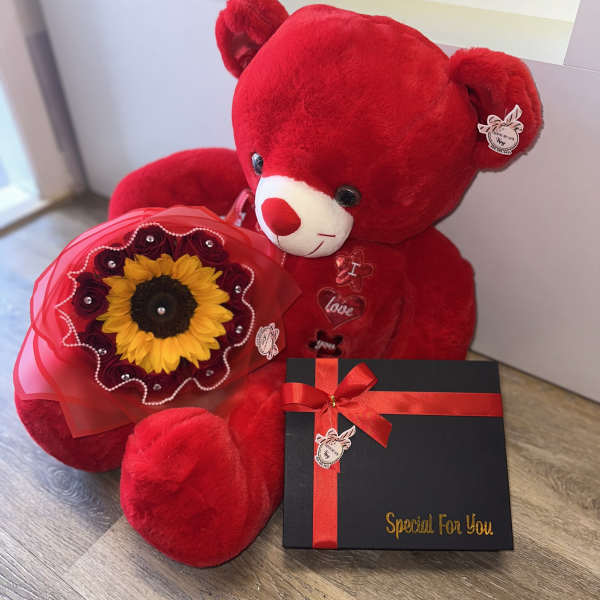 Red teddy bear with a sunflower bouquet and a black gift box with ribbon