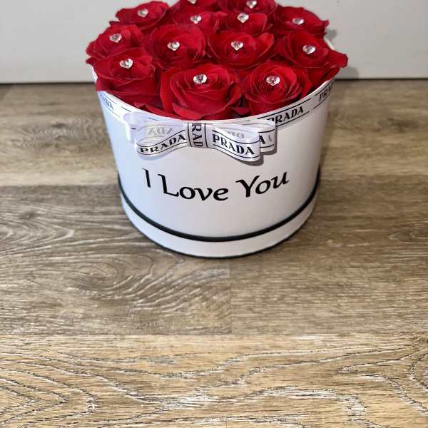 Red roses arranged in a white round box with a ribbon and "I Love You" text