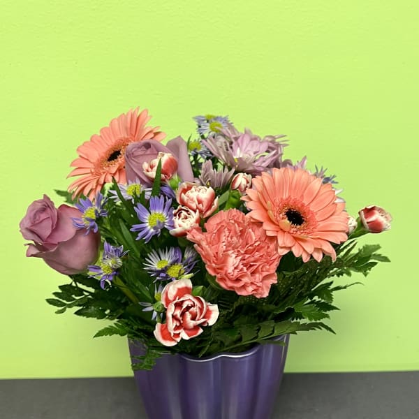 Mixed bouquet of pink and purple flowers in a purple vase