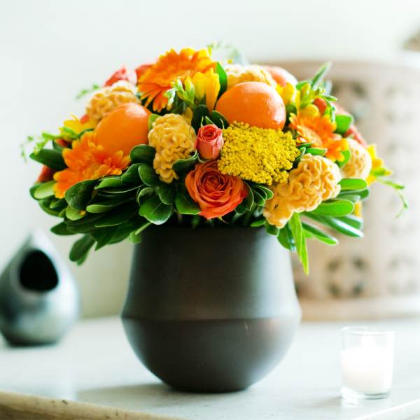 Orange and yellow floral arrangement in a dark vase
