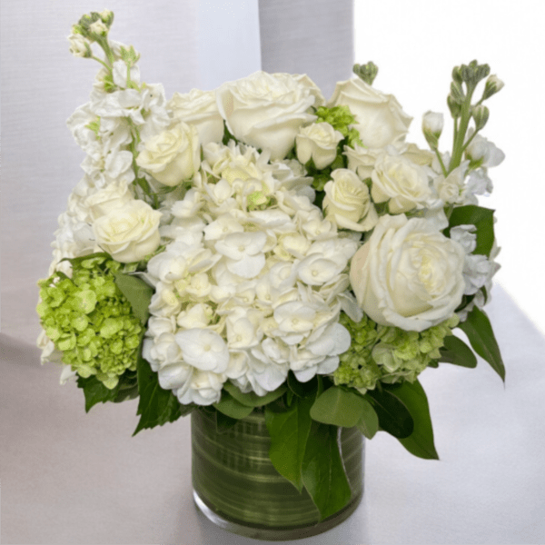 White roses and hydrangeas arranged in a glass vase