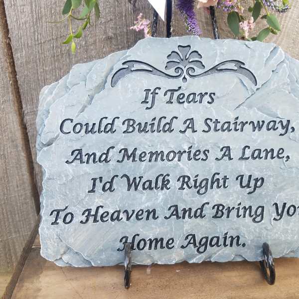 A memorial stone plaque with a sympathy quote on a stand.