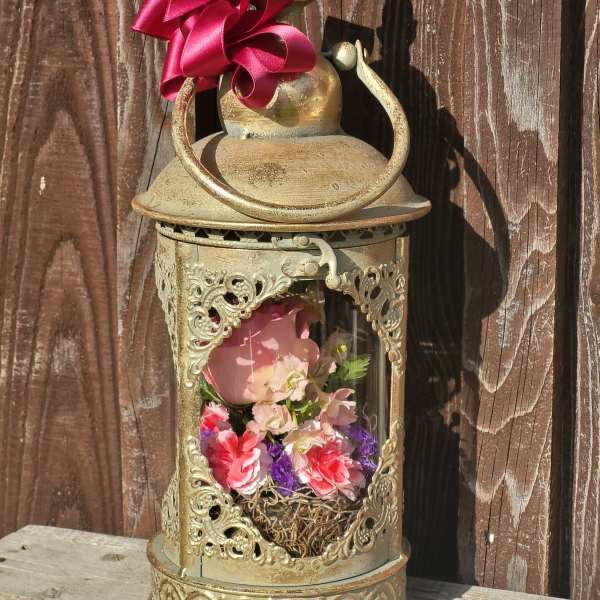 Decorative lantern with pink and purple flowers inside and a magenta ribbon bow on top