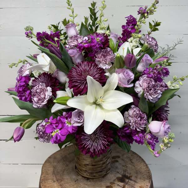 Purple and white mixed bouquet in a woven basket vase