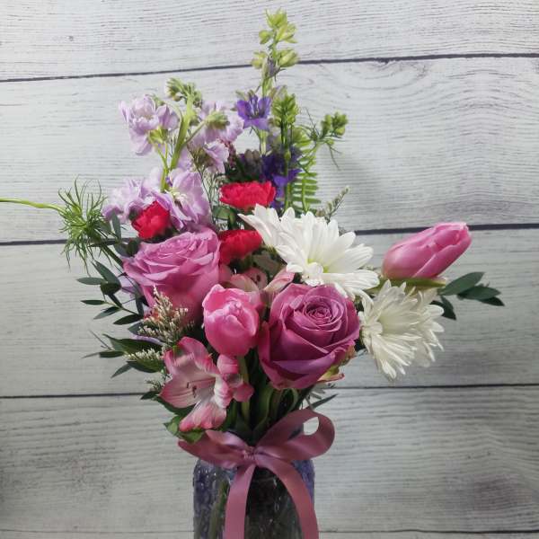 Pink and white mixed bouquet in a glass vase with a ribbon