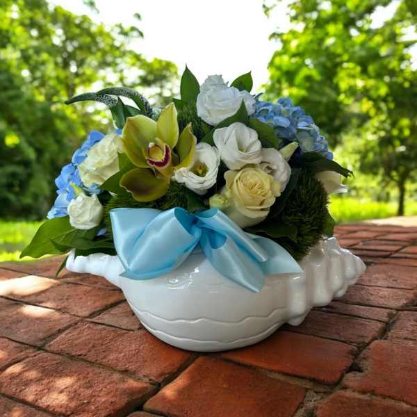 Bouquet of white and blue flowers in a white ceramic bowl with a blue ribbon