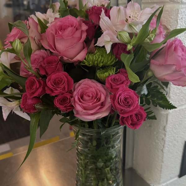 Vase arrangement of pink roses, white alstroemeria, and green button mums in a clear glass cylinder