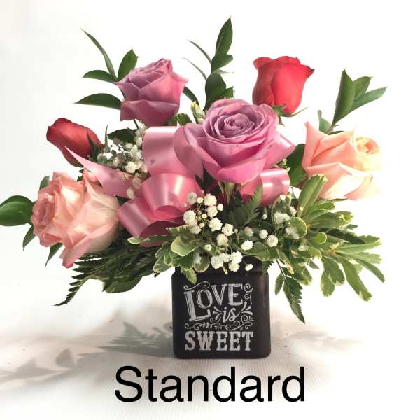 Pink and red roses in a black vase with a "Love is Sweet" design