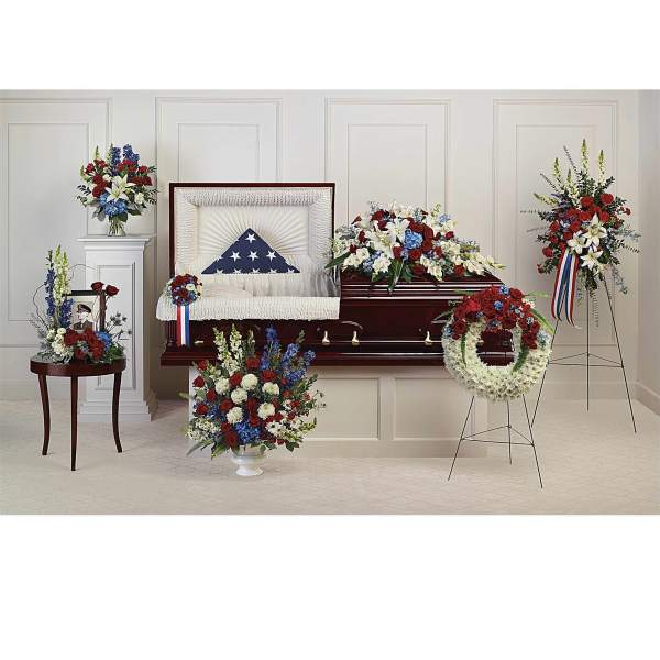 Casket surrounded by red, white, and blue funeral flower arrangements
