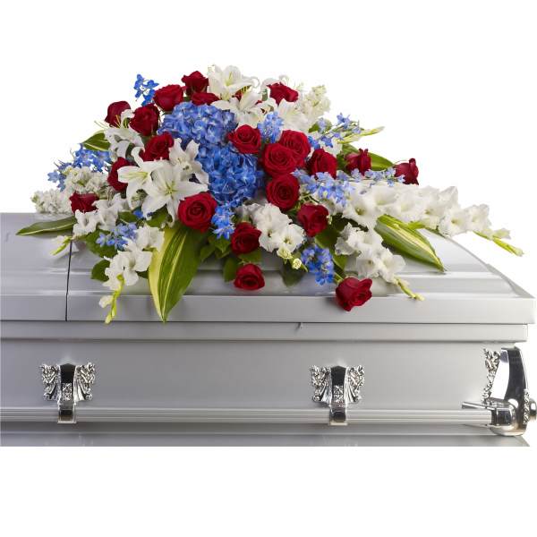 Red roses, white lilies, and blue flowers arranged on a silver casket