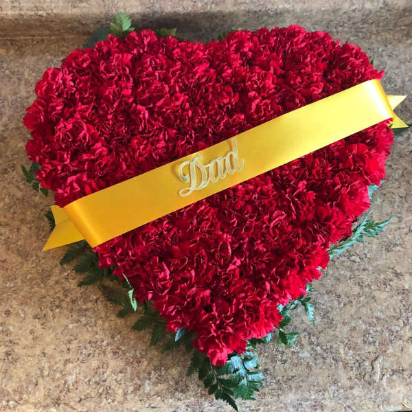 Heart-shaped red carnation arrangement with a yellow ribbon reading Dad