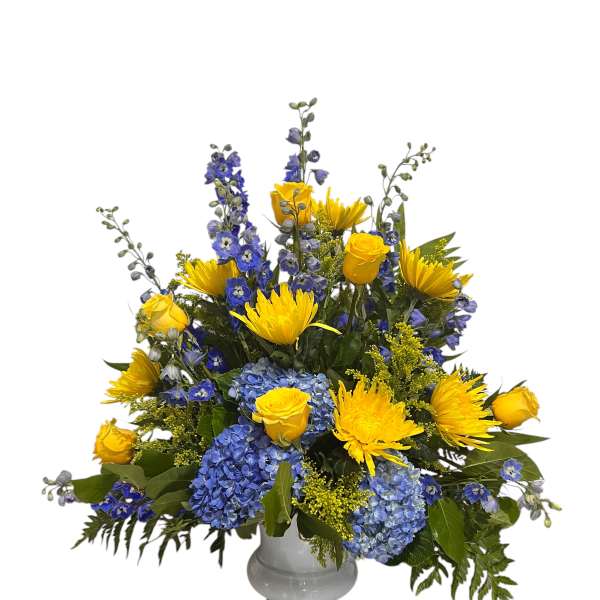 Yellow roses and blue flowers arranged in a gray vase
