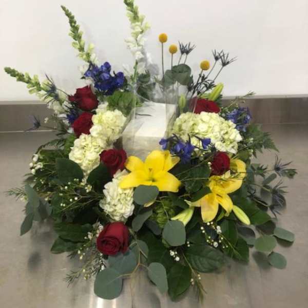 Low floral arrangement with red roses, yellow lilies, and white hydrangeas
