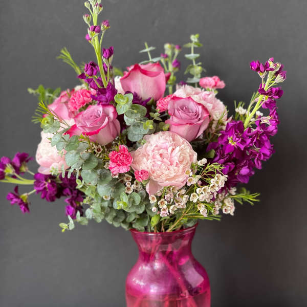 Pink and purple bouquet in a magenta glass vase
