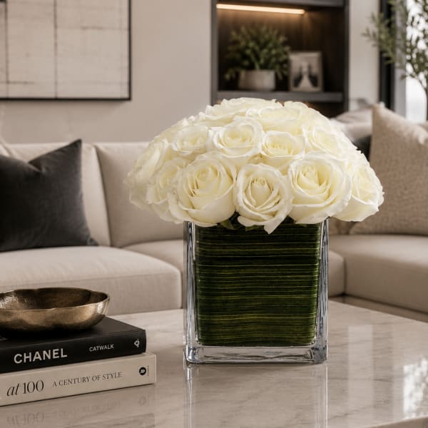 White rose arrangement in a clear square vase on a table