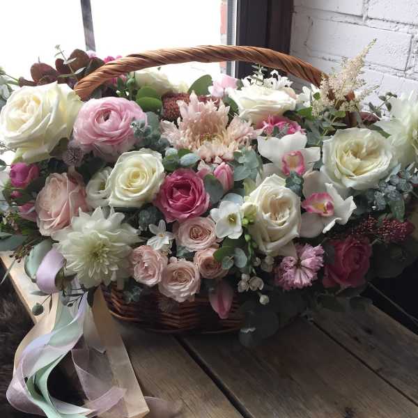 Basket arrangement of pink and white roses with mixed blooms and ribbon