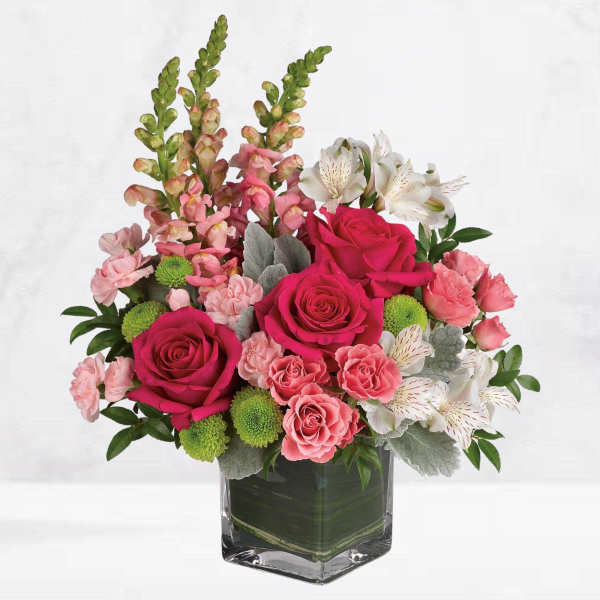 Pink roses and white alstroemeria in a clear square vase