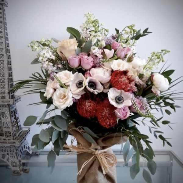 Mixed bouquet of pink, white, and red flowers in a burlap-wrapped vase