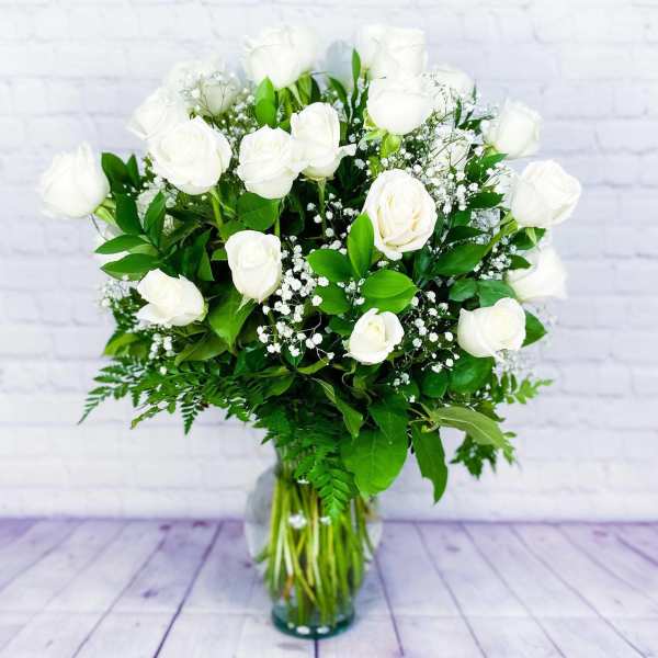 White rose bouquet in a clear glass vase with baby's breath