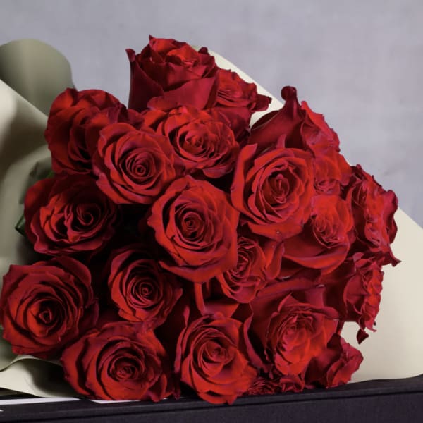 Bouquet of red roses wrapped in pale paper