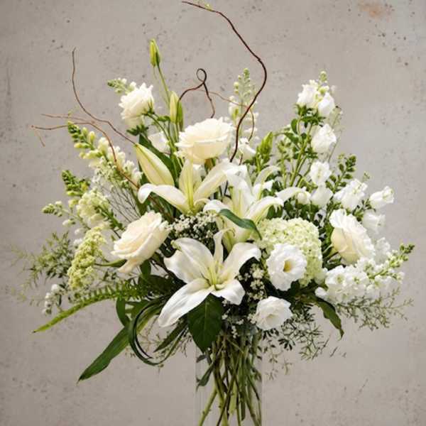 White lilies and roses arranged in a clear glass vase