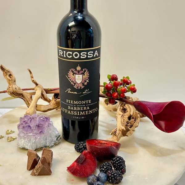 Wine bottle arranged with berries, chocolate, and a purple crystal on a round table