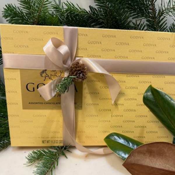 Gift box of Godiva assorted chocolates tied with a ribbon and pine sprig