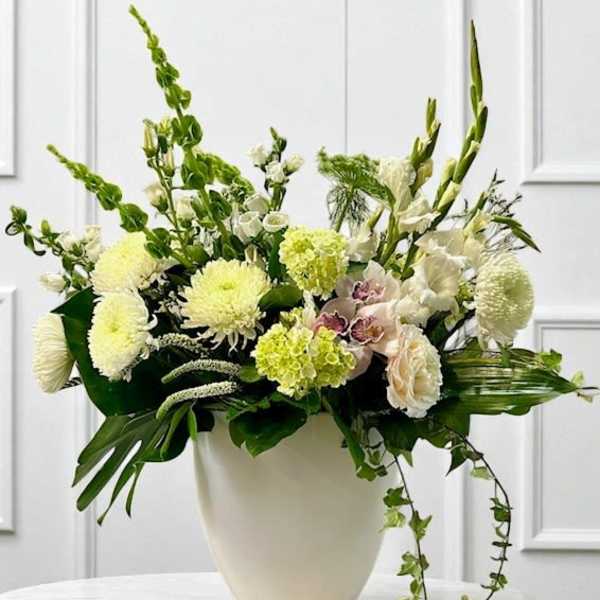 White floral arrangement in a cream vase with tall green stems