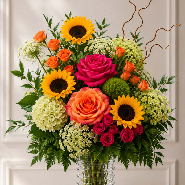 Mixed bouquet of roses and sunflowers in a clear glass vase