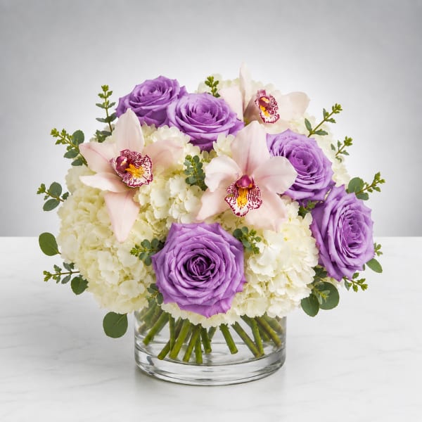 Purple roses and pale orchids in a glass vase