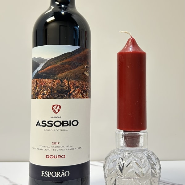 Wine bottle beside a red candle in a clear glass holder