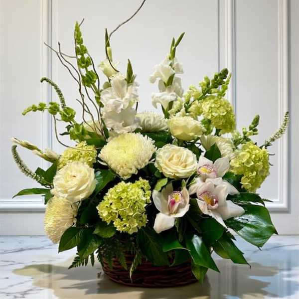 White and pale green floral arrangement in a wicker basket