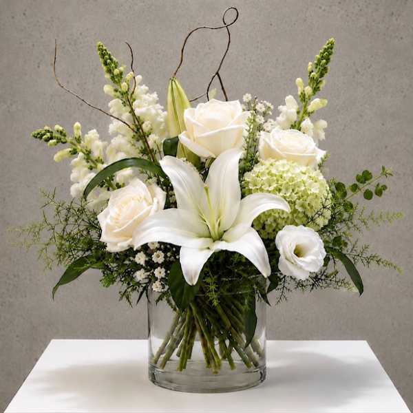 White roses and lilies arranged in a clear glass vase