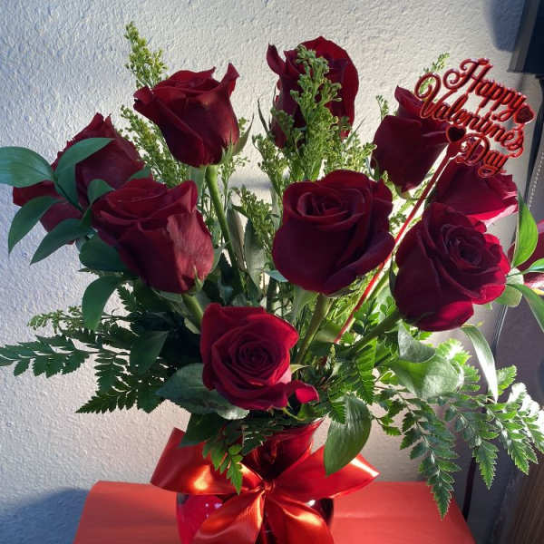 Bouquet of red roses in a glass vase with a Valentine sign