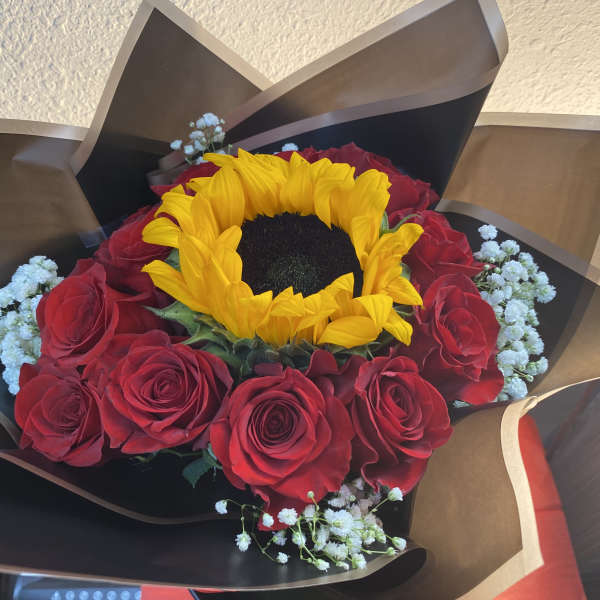Bouquet of red roses with a yellow sunflower and white baby's breath
