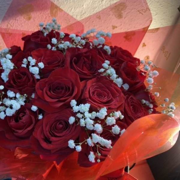 Bouquet of red roses with light blue baby's breath in pink wrapping