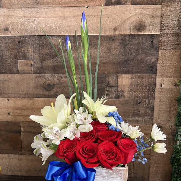 Red roses and white lilies in a wooden box with a blue ribbon