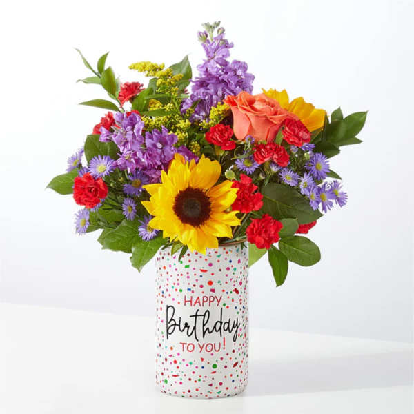 Mixed bouquet in a birthday vase with a sunflower, roses, and purple blooms