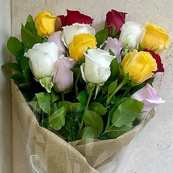 Wrapped bouquet of red, white, yellow, and pink roses in patterned paper with a white ribbon