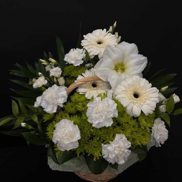 White flowers and green blooms arranged in a wicker basket
