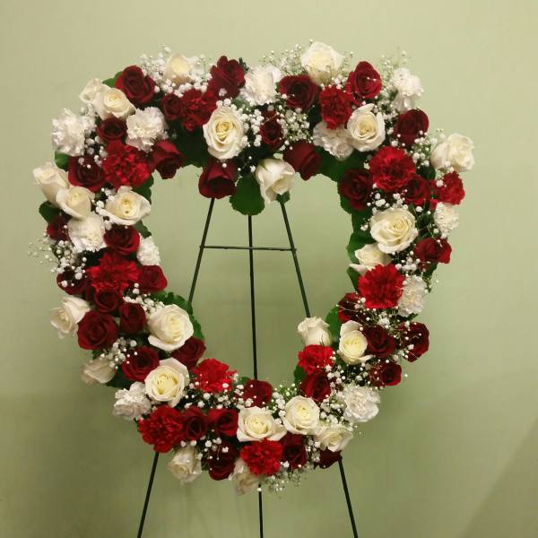 Heart-shaped floral wreath of red and white roses on a stand