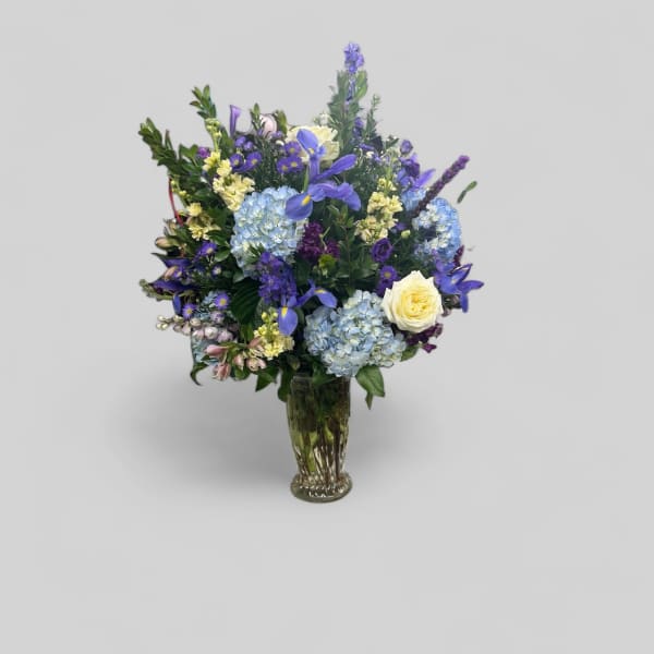 Mixed blue and purple flower arrangement in a glass vase