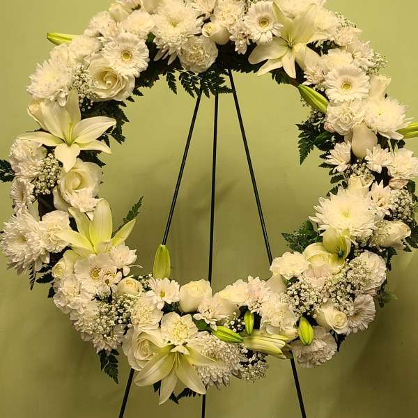 White floral wreath on a black stand