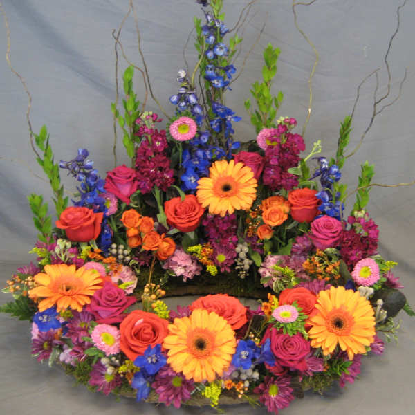 Colorful floral wreath with roses, gerbera daisies, and blue flowers