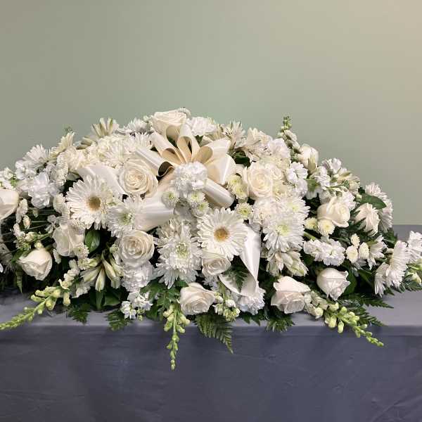White floral casket spray with roses and daisies