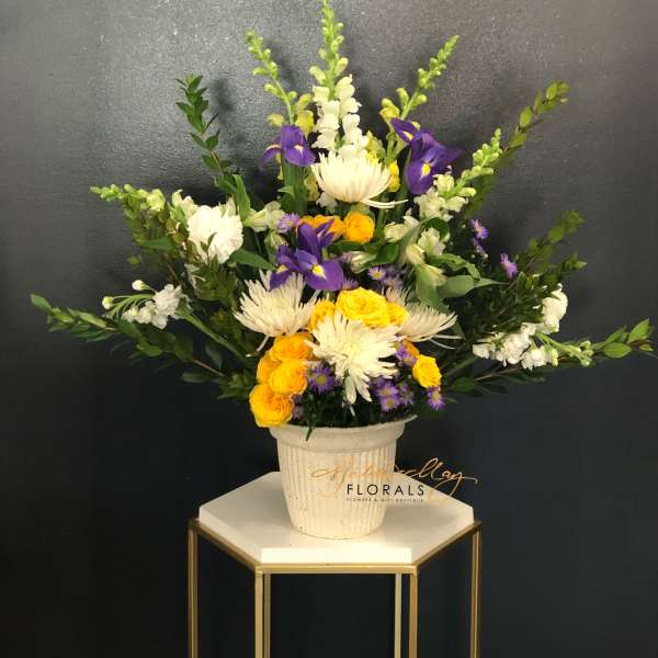 Mixed bouquet in a white pot with yellow, white, and purple flowers