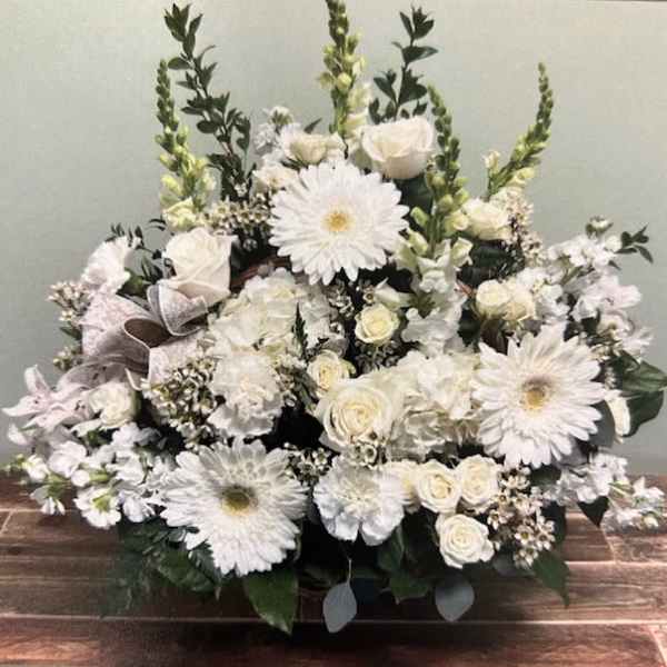 White floral arrangement with daisies and roses in a low container