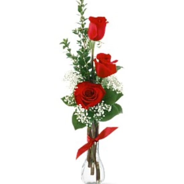 Three red roses in a clear glass vase with a red ribbon