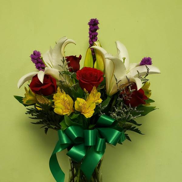 Bouquet of red roses, white lilies, and yellow alstroemeria in a glass vase
