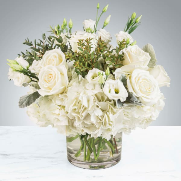 White roses and hydrangeas in a clear glass vase